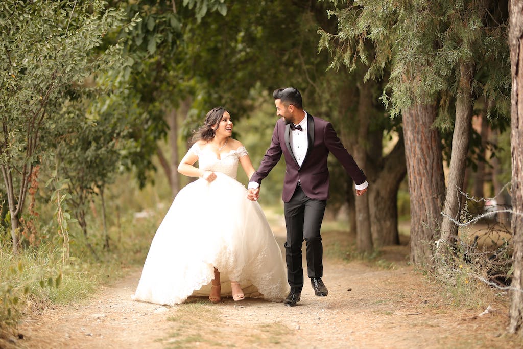 person in wedding dress and suit running on a dirt road.