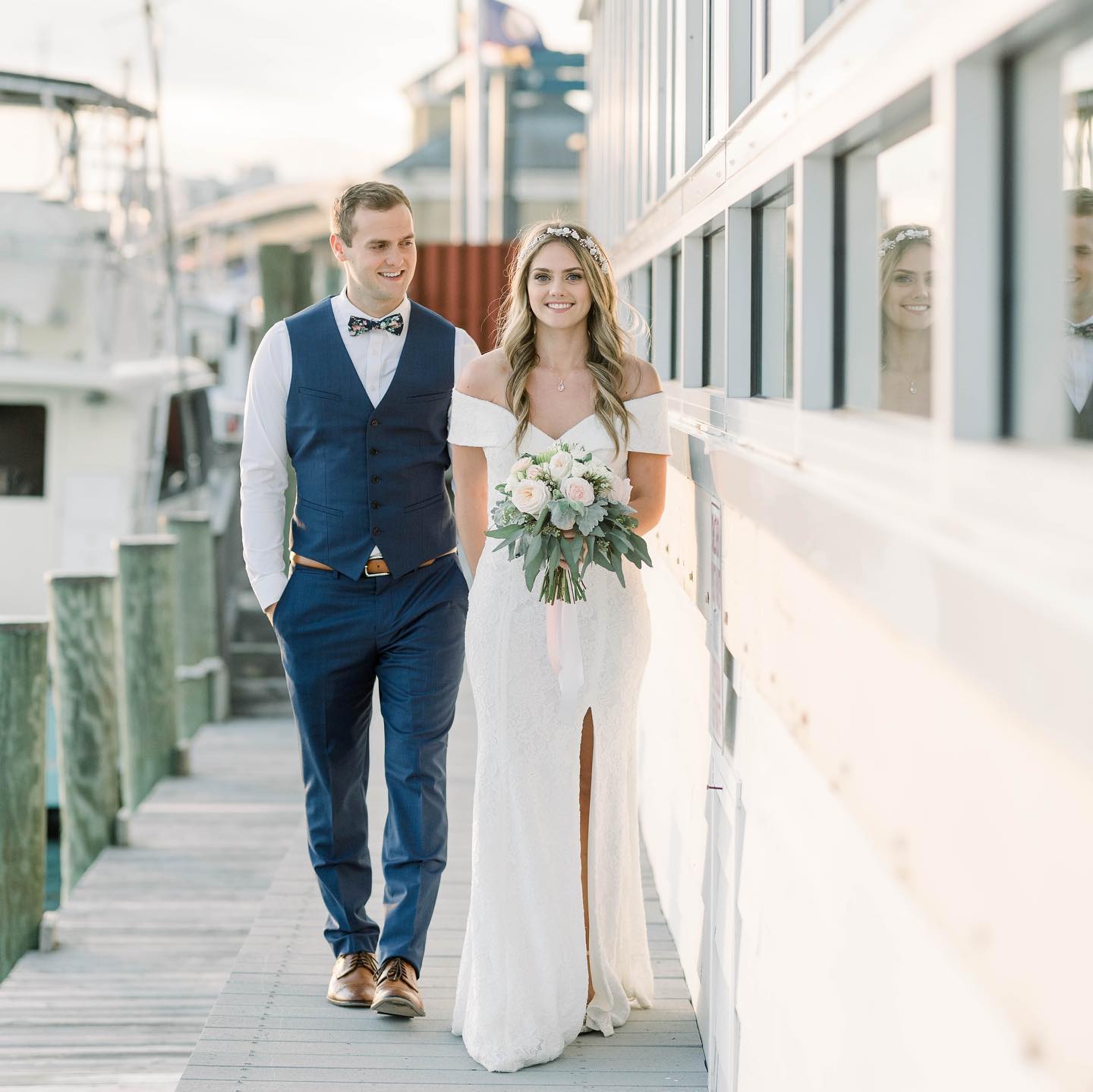 bride and groom walking hand and hand on a dock